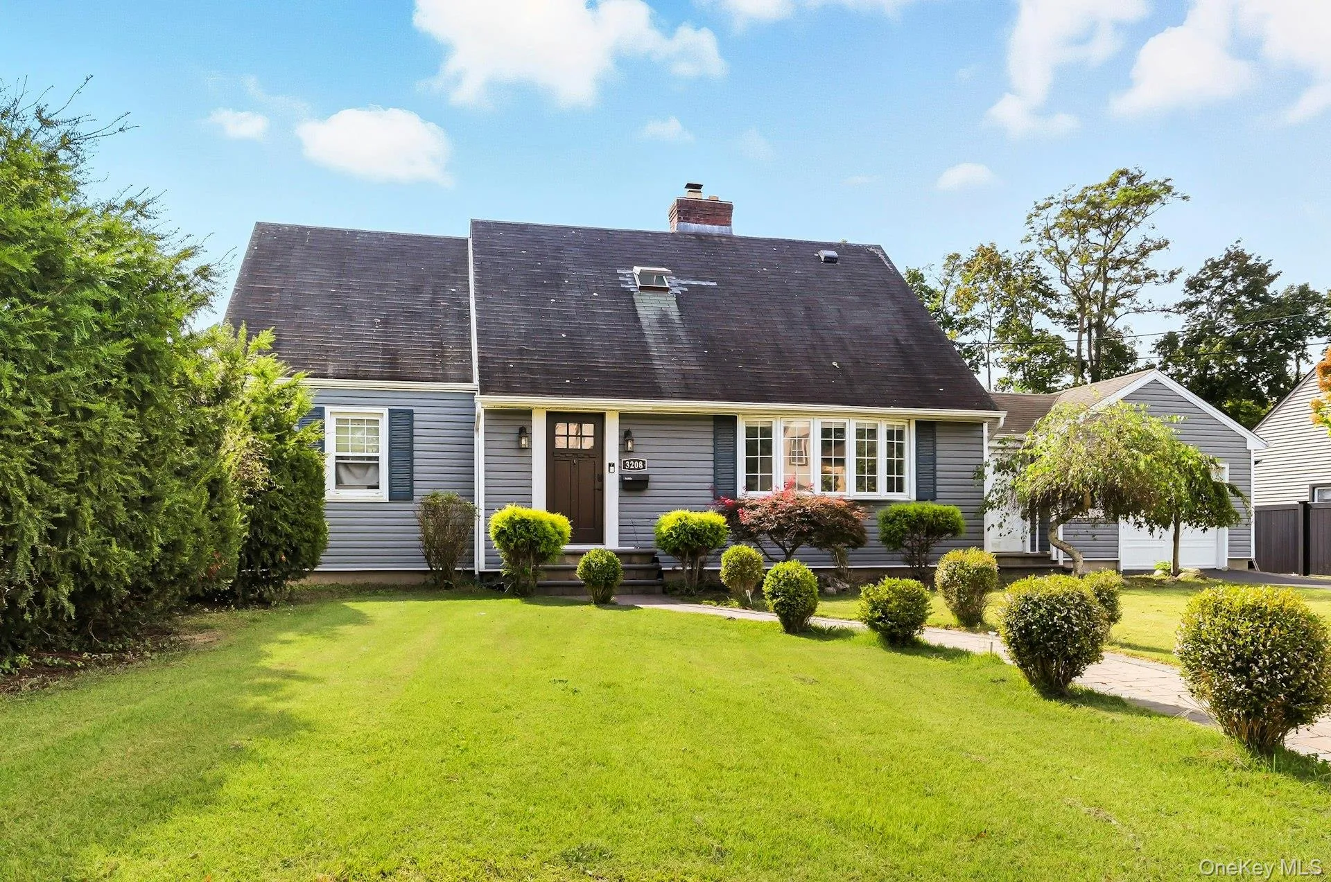 View of front of house with a front lawn, a chimney, roof with shingles, and entry steps View of front of house with a front lawn, a chimney, roof with shingles, and entry steps
