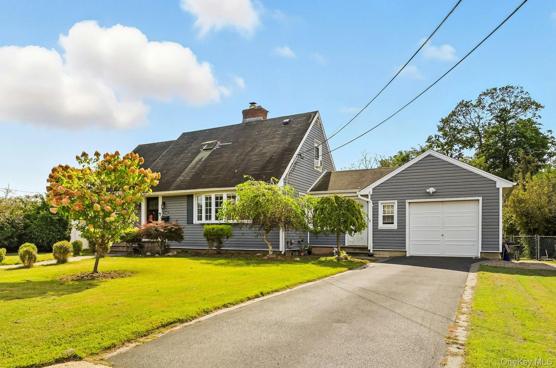 Cape cod home featuring a garage, driveway, a chimney, and a shingled roof Cape cod home featuring a garage, driveway, a chimney, and a shingled roof
