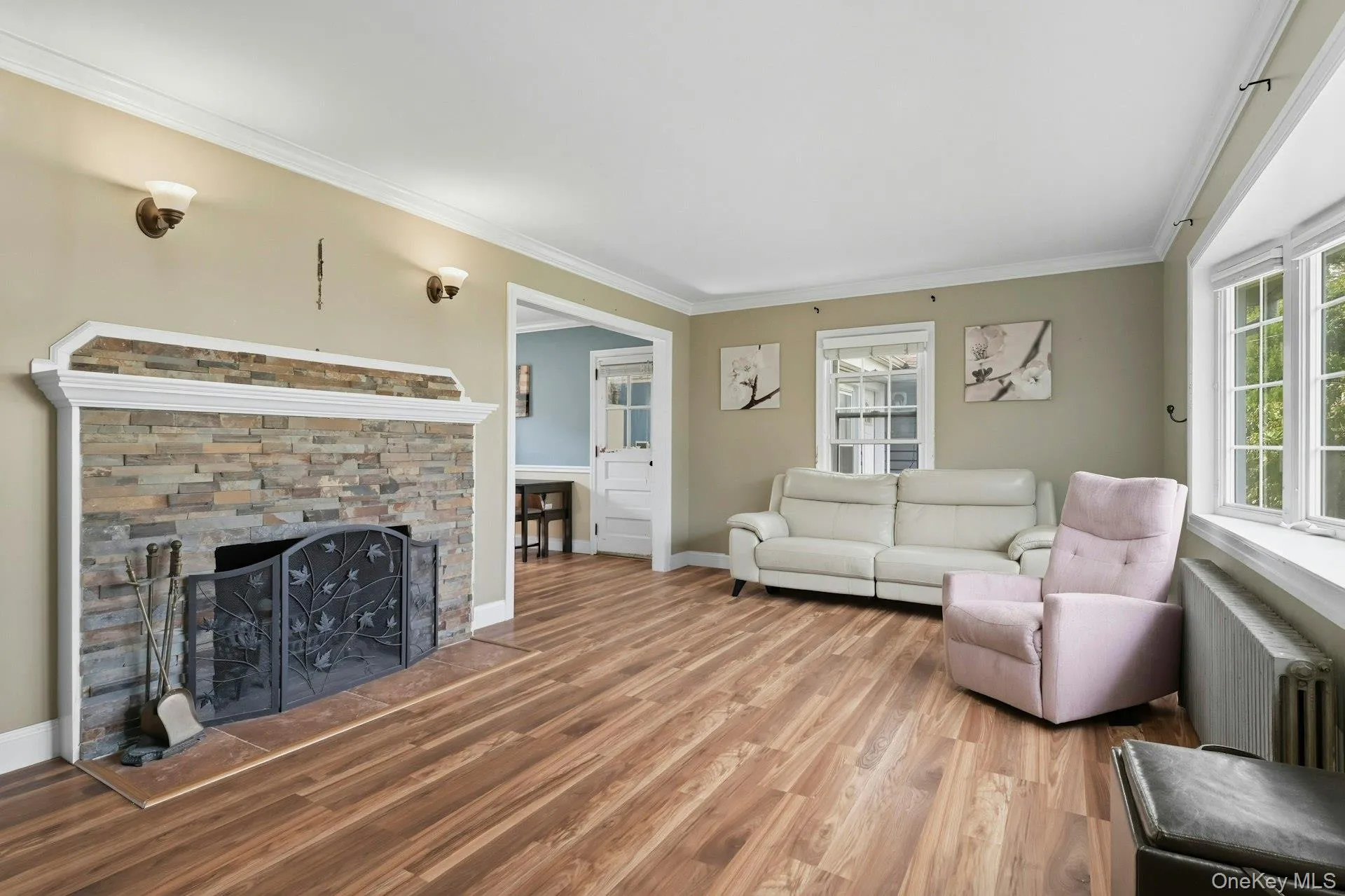 Living area with ornamental molding, a fireplace, radiator, and wood finished floors Living area with ornamental molding, a fireplace, radiator, and wood finished floors