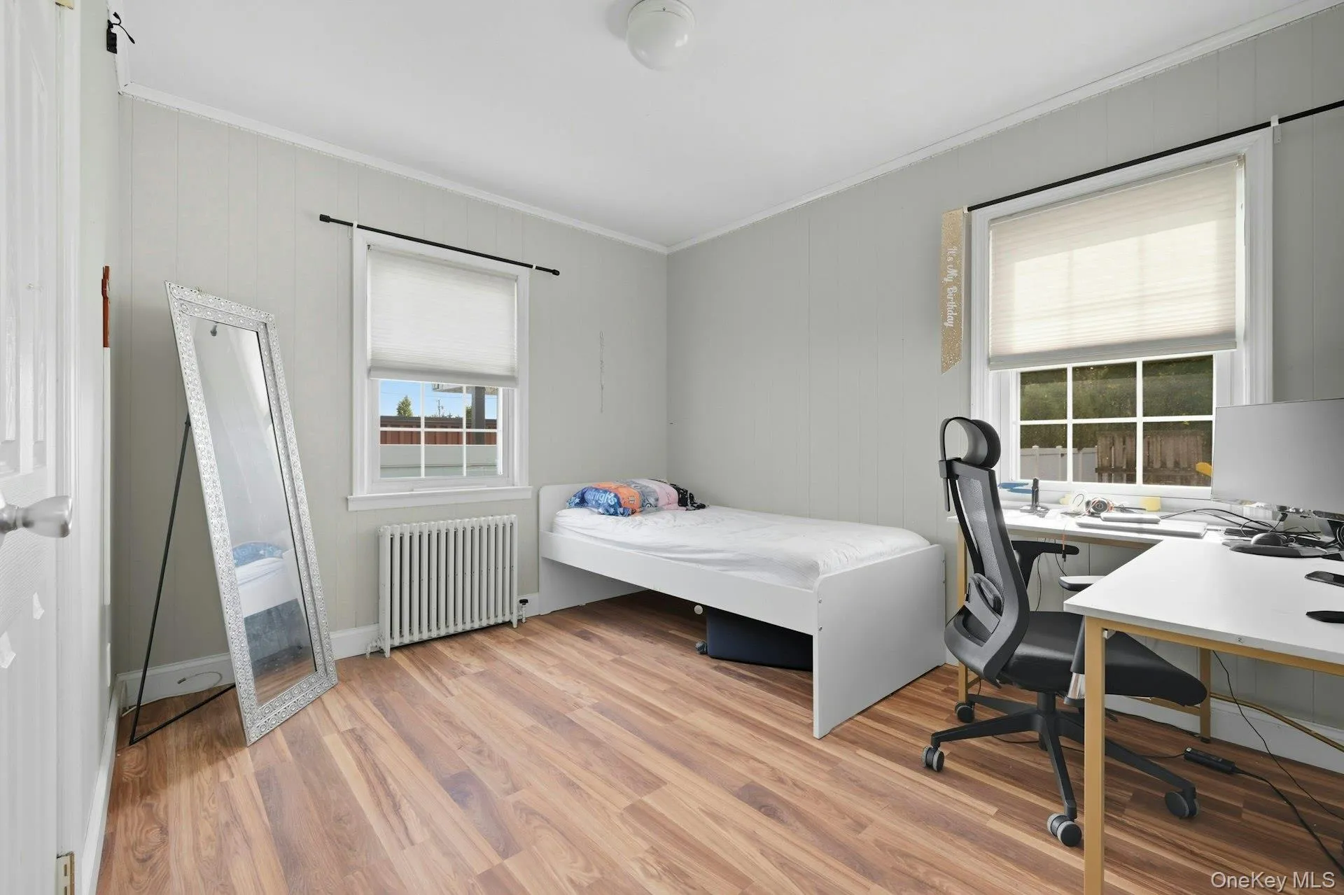 Bedroom with radiator heating unit, light wood-style floors, crown molding Bedroom with radiator heating unit, light wood-style floors, crown molding