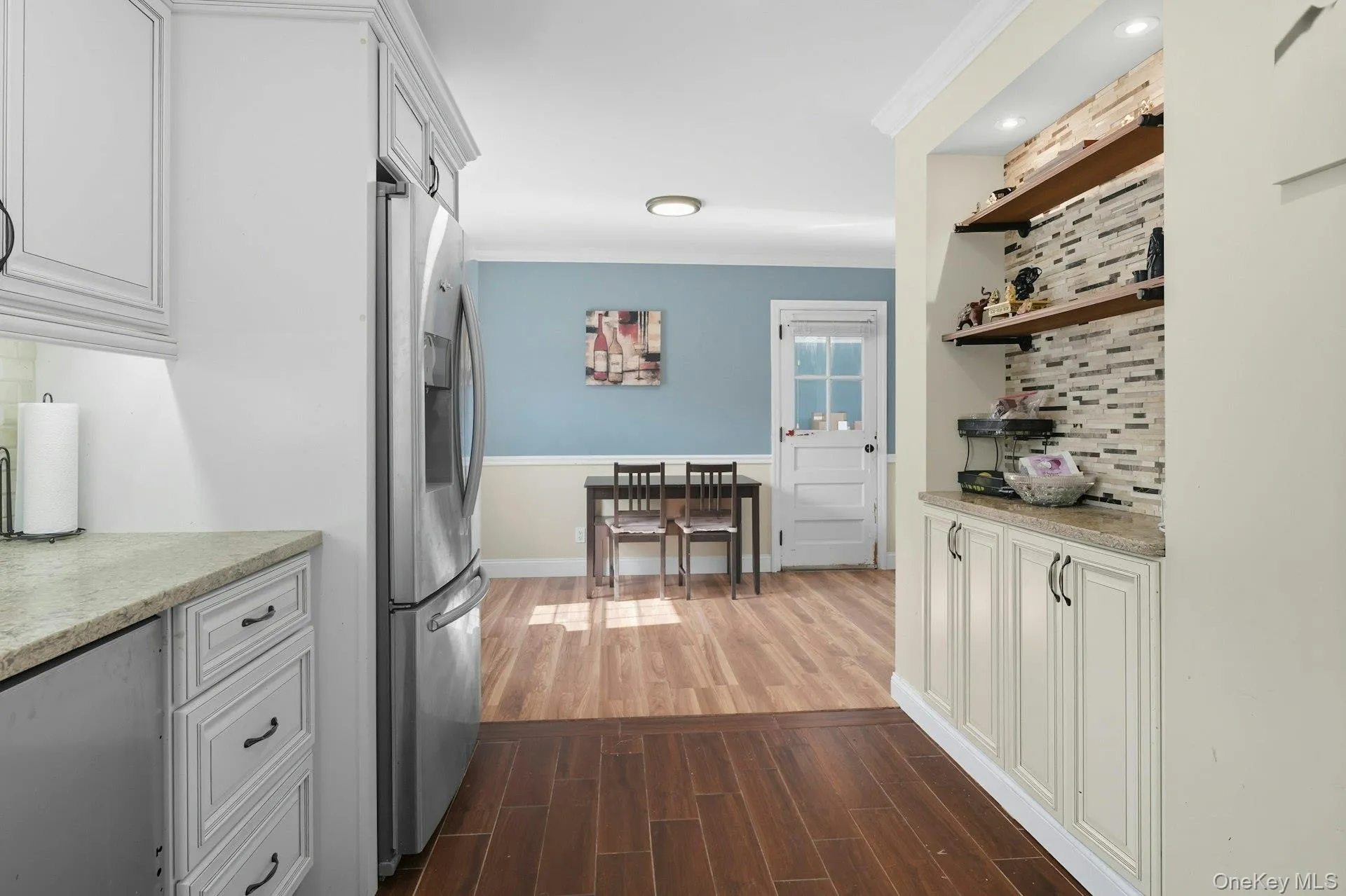 Kitchen with tasteful backsplash, white cabinetry, light stone countertops, and crown molding Kitchen with tasteful backsplash, white cabinetry, light stone countertops, and crown molding
