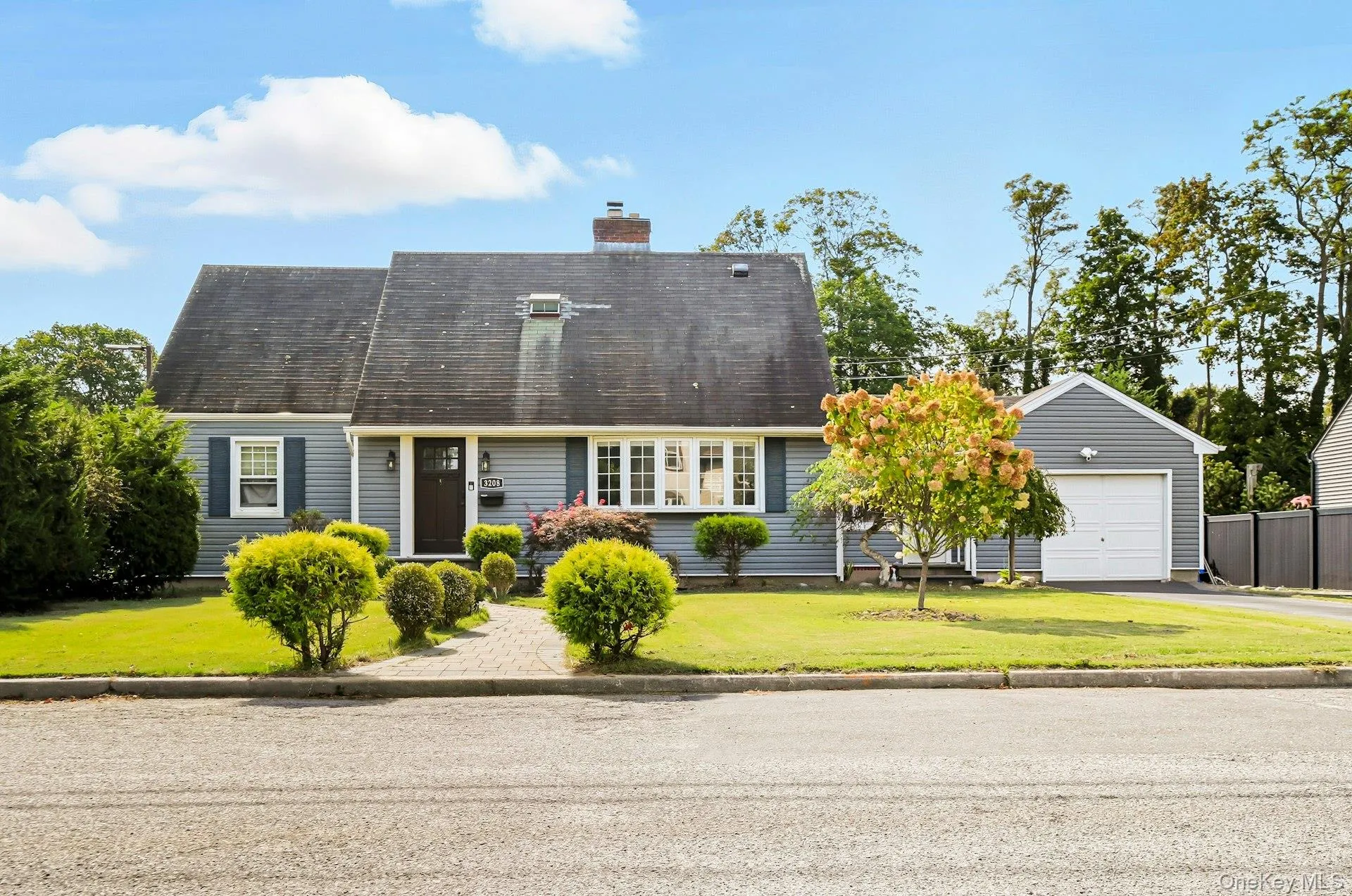 Cape cod-style house featuring a front lawn, a garage, a chimney, and driveway Cape cod-style house featuring a front lawn, a garage, a chimney, and driveway
