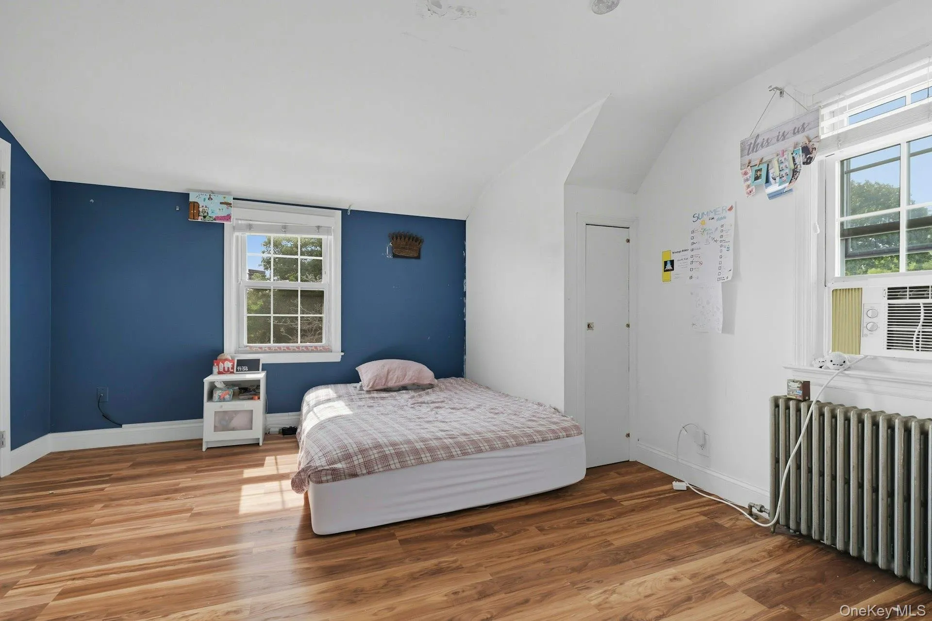 Bedroom featuring radiator, wood finished floors, vaulted ceiling Bedroom featuring radiator, wood finished floors, vaulted ceiling