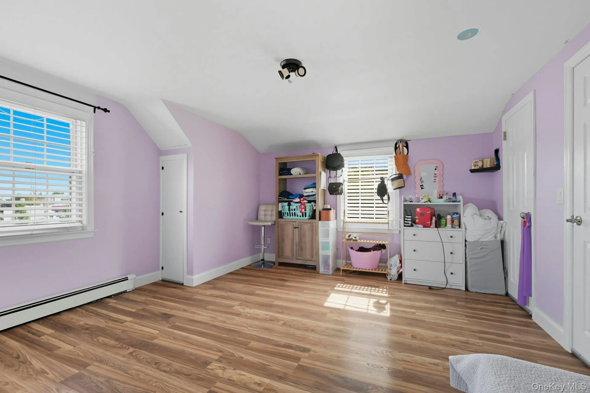 Bedroom featuring radiator, wood finished floors, vaulted ceiling Bedroom featuring radiator, wood finished floors, vaulted ceiling