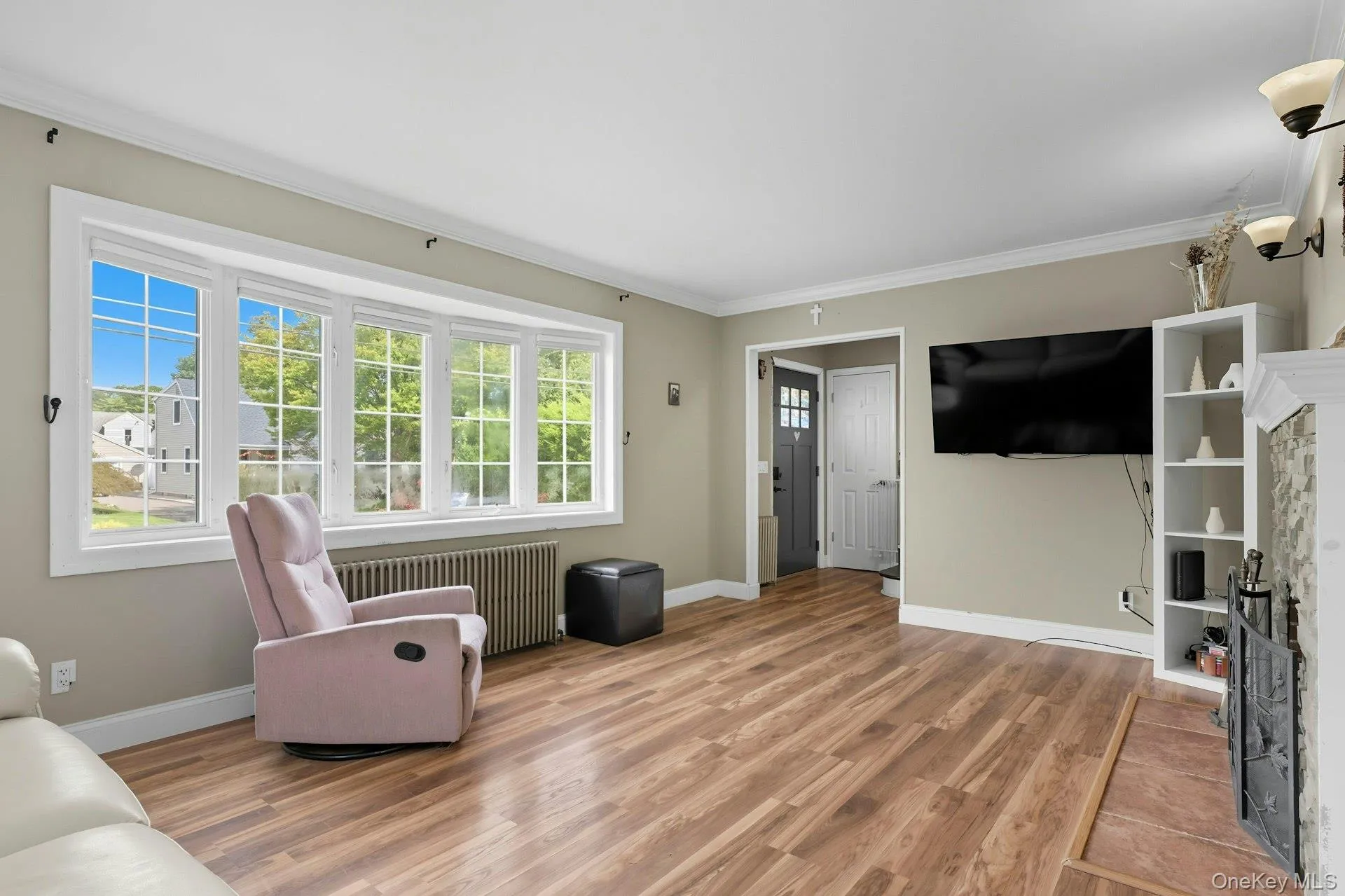 Living room featuring ornamental molding, radiator heating unit, light wood-type flooring, and a fireplace Living room featuring ornamental molding, radiator heating unit, light wood-type flooring, and a fireplace