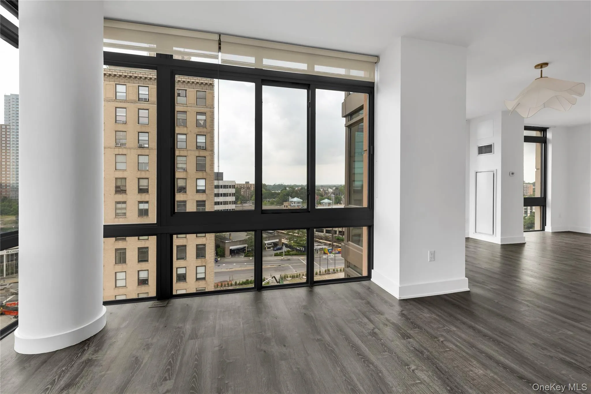 Living room and dining room nook with plenty of natural light, a wall of windows, wood finished floors, and a city view Living room and dining room nook with plenty of natural light, a wall of windows, wood finished floors, and a city view