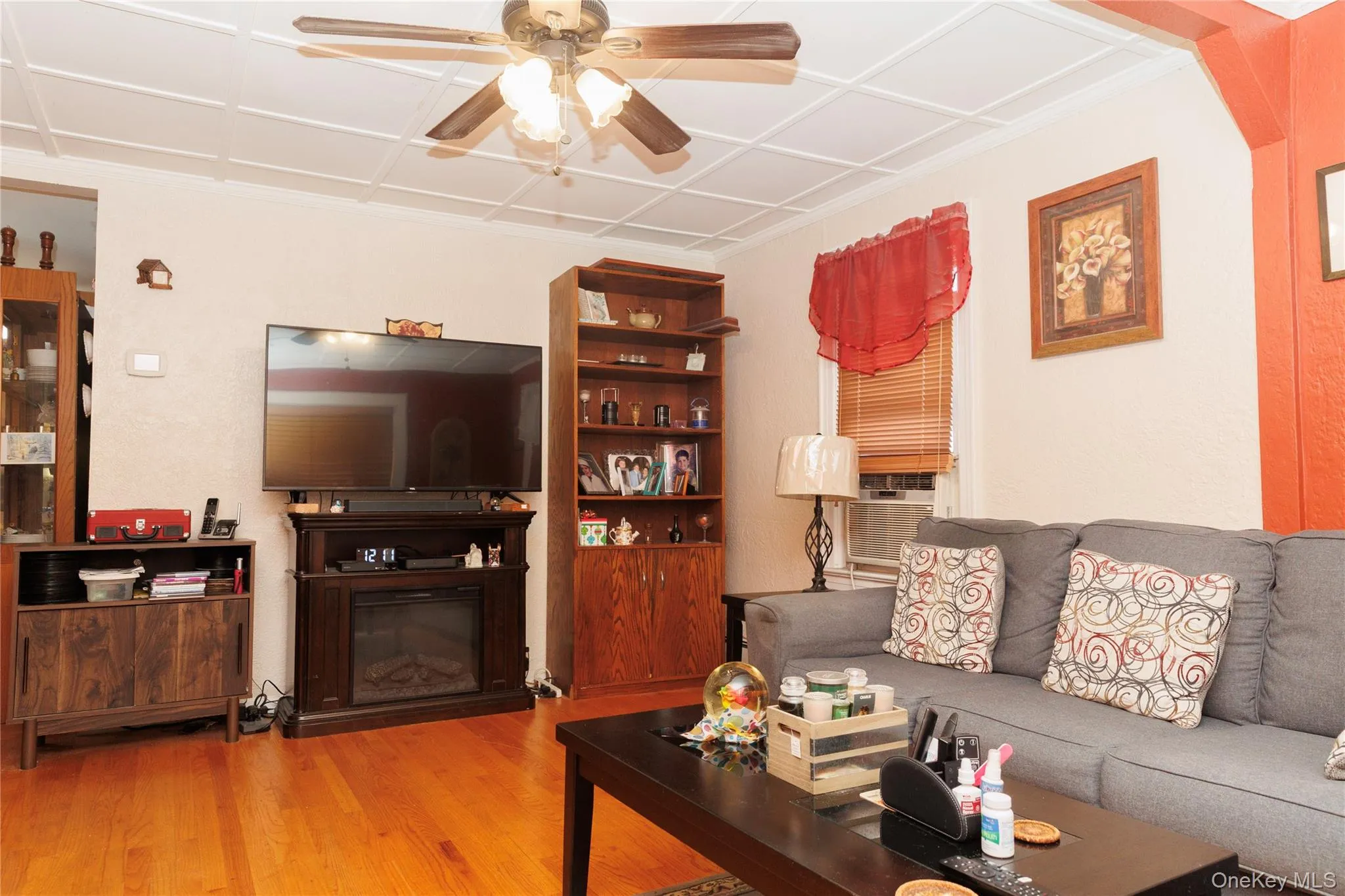 Living room featuring light wood-style flooring, cooling unit, ceiling fan, and a glass covered fireplace Living room featuring light wood-style flooring, cooling unit, ceiling fan, and a glass covered fireplace