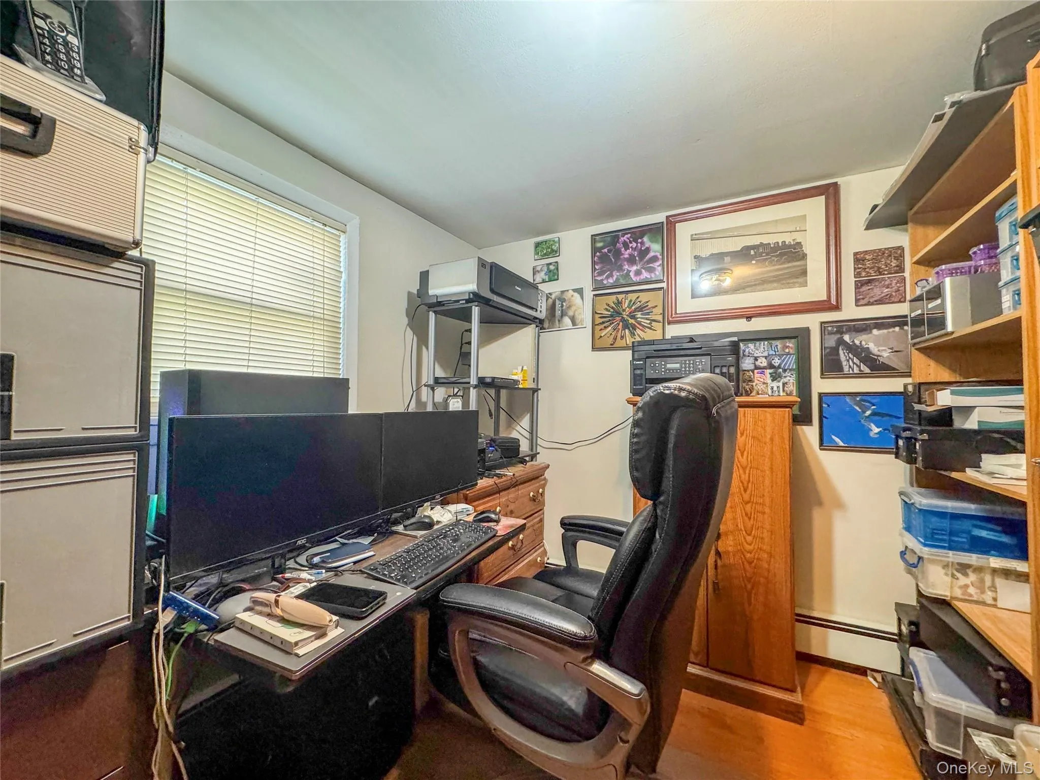 Home office with light wood-type flooring and a baseboard heating unit Home office with light wood-type flooring and a baseboard heating unit