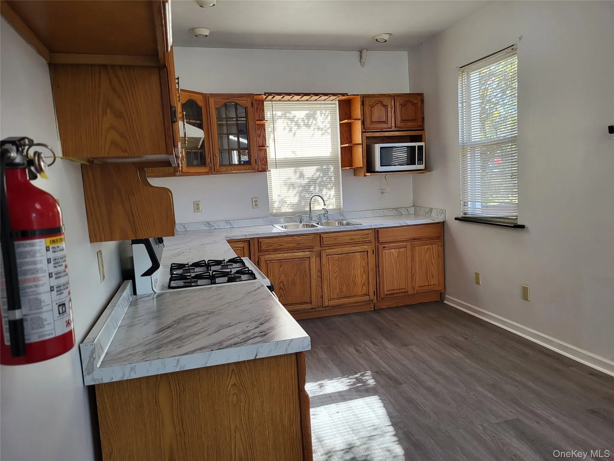 Kitchen featuring brown cabinetry, healthy amount of natural light, light countertops, and open shelves Kitchen featuring brown cabinetry, healthy amount of natural light, light countertops, and open shelves