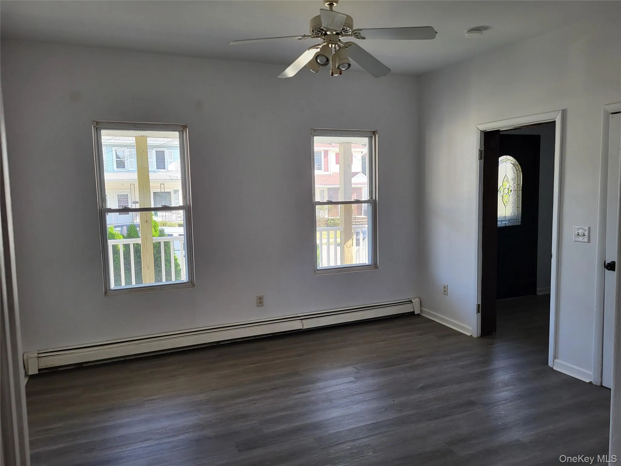 Empty room featuring baseboard heating, dark wood finished floors, and a ceiling fan Empty room featuring baseboard heating, dark wood finished floors, and a ceiling fan