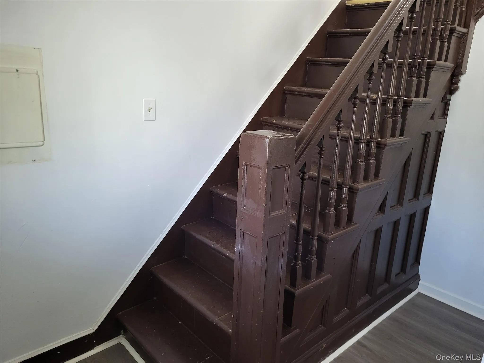 Stairway featuring wood finished floors and electric panel Stairway featuring wood finished floors and electric panel