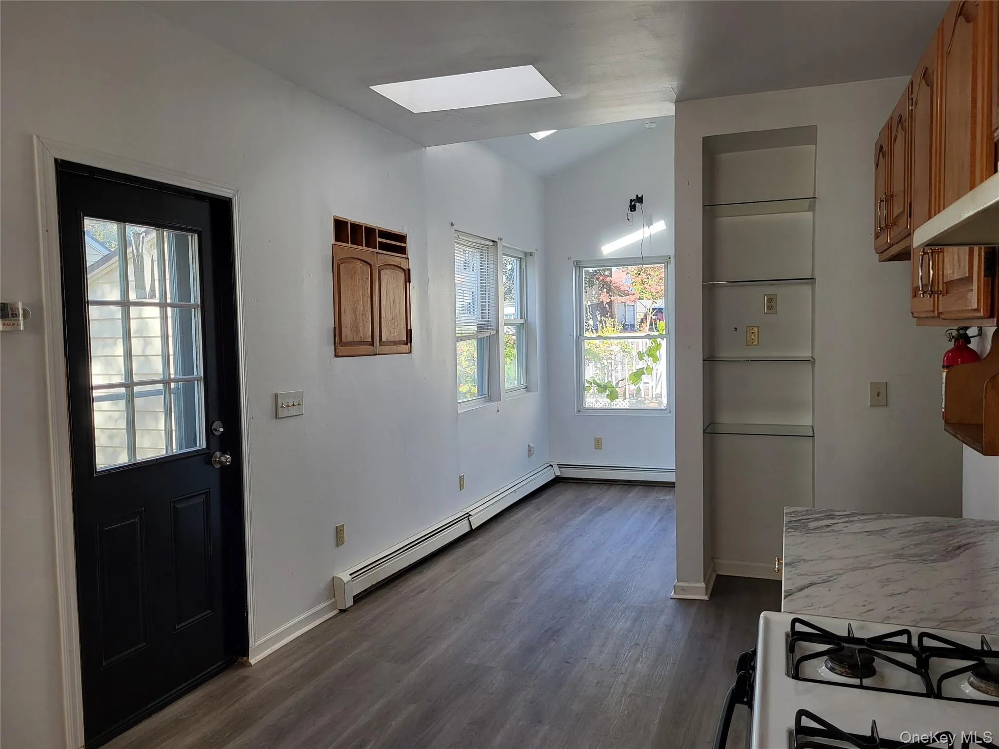 Kitchen featuring gas range gas stove, dark wood-style flooring, a skylight, brown cabinets, and light countertops Kitchen featuring gas range gas stove, dark wood-style flooring, a skylight, brown cabinets, and light countertops