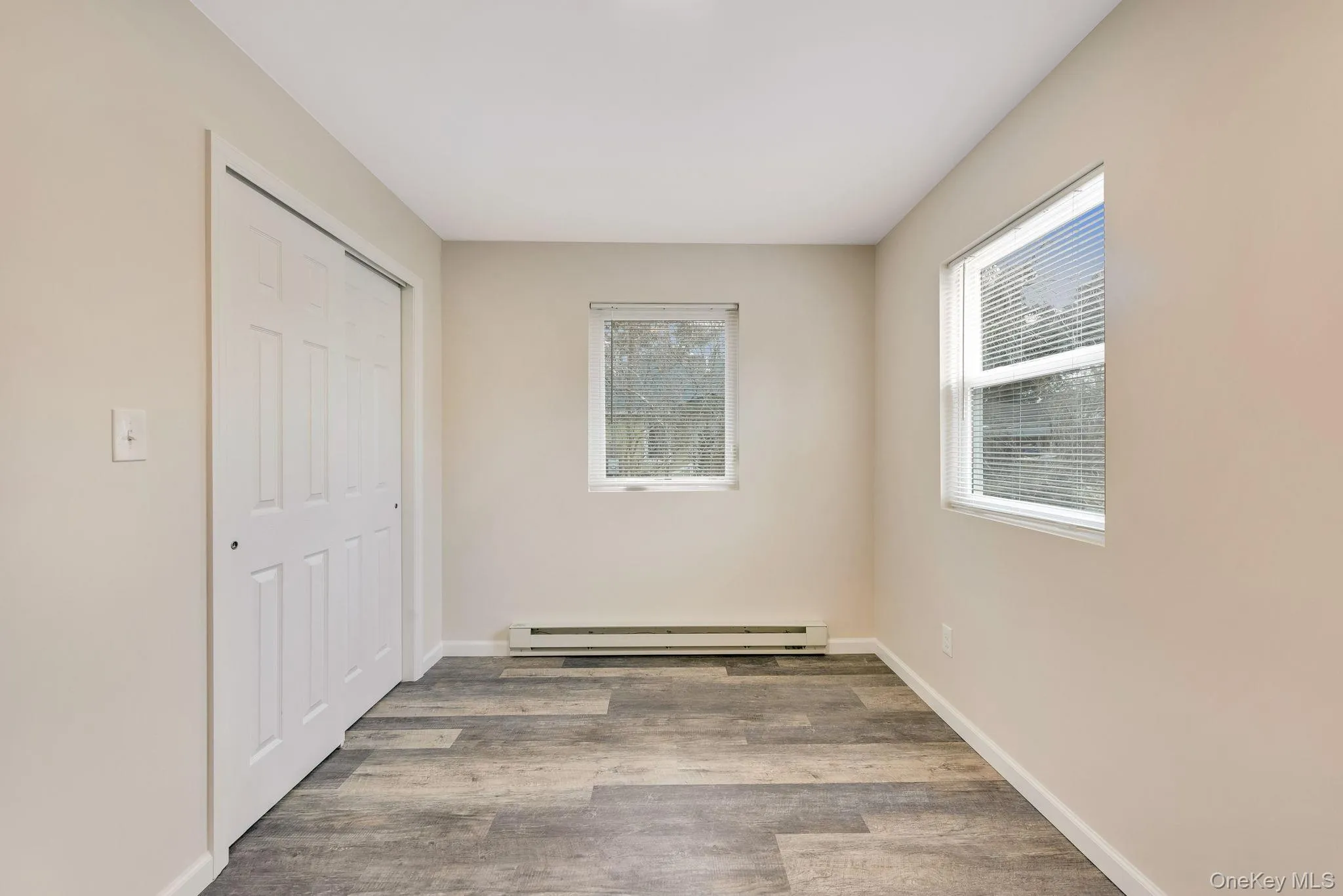 Unfurnished bedroom with a closet, light wood-type flooring, and a baseboard radiator Unfurnished bedroom with a closet, light wood-type flooring, and a baseboard radiator