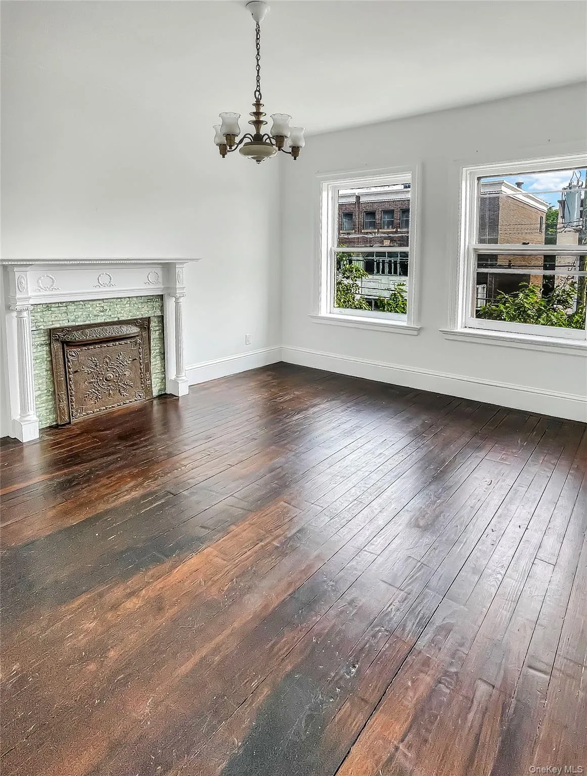 Unfurnished living room featuring dark wood-style flooring, a chandelier, and a high end fireplace Unfurnished living room featuring dark wood-style flooring, a chandelier, and a high end fireplace