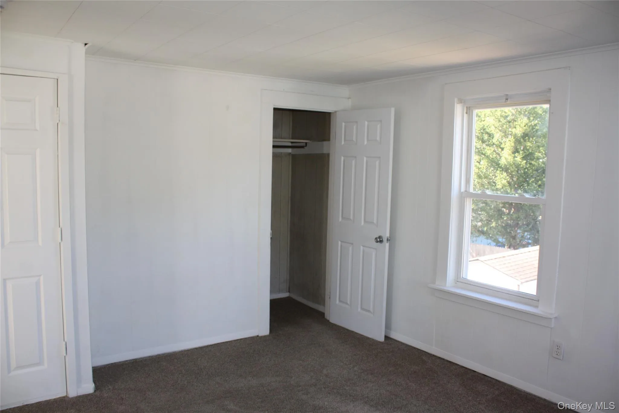 Unfurnished bedroom featuring dark colored carpet, a closet, and crown molding Unfurnished bedroom featuring dark colored carpet, a closet, and crown molding