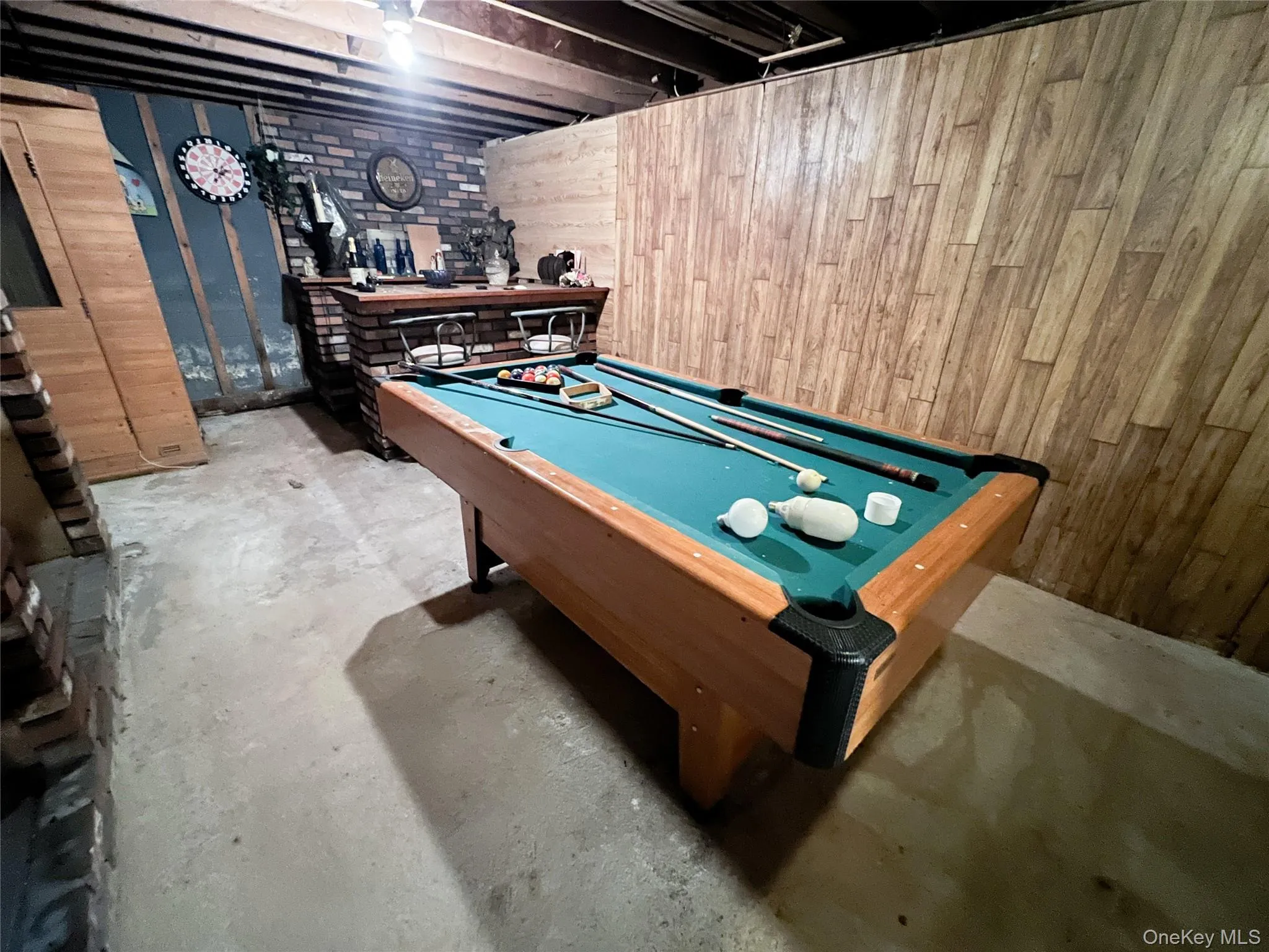 Game room with unfinished concrete flooring, pool table, and wood walls Game room with unfinished concrete flooring, pool table, and wood walls