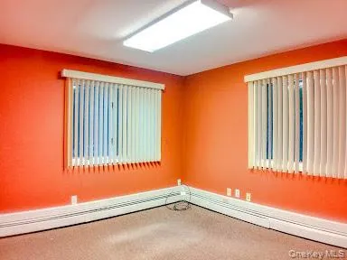 Unfurnished room featuring carpet floors and baseboard heating Unfurnished room featuring carpet floors and baseboard heating