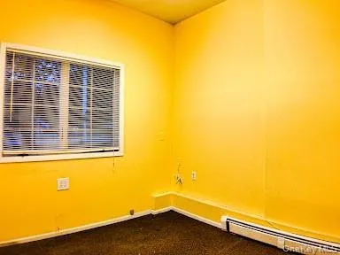 Unfurnished room with baseboard heating and dark carpet Unfurnished room with baseboard heating and dark carpet