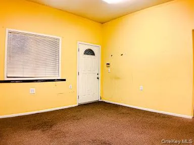 Entryway featuring dark colored carpet and baseboards Entryway featuring dark colored carpet and baseboards