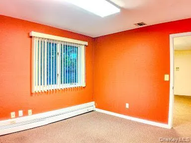 Carpeted empty room with a baseboard radiator and baseboards Carpeted empty room with a baseboard radiator and baseboards