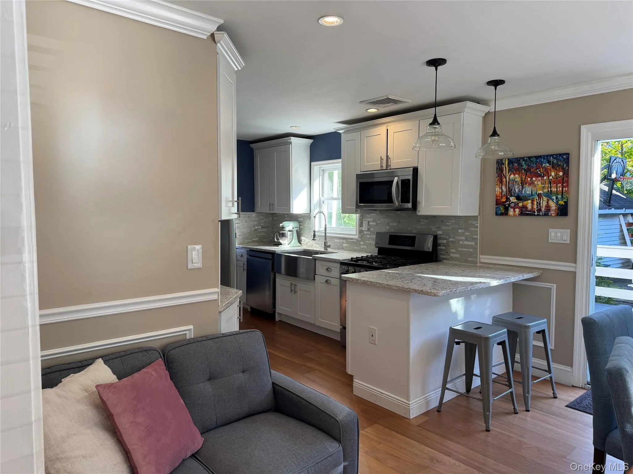 Kitchen with a breakfast bar, a peninsula, tasteful backsplash, appliances with stainless steel finishes, and ornamental molding Kitchen with a breakfast bar, a peninsula, tasteful backsplash, appliances with stainless steel finishes, and ornamental molding