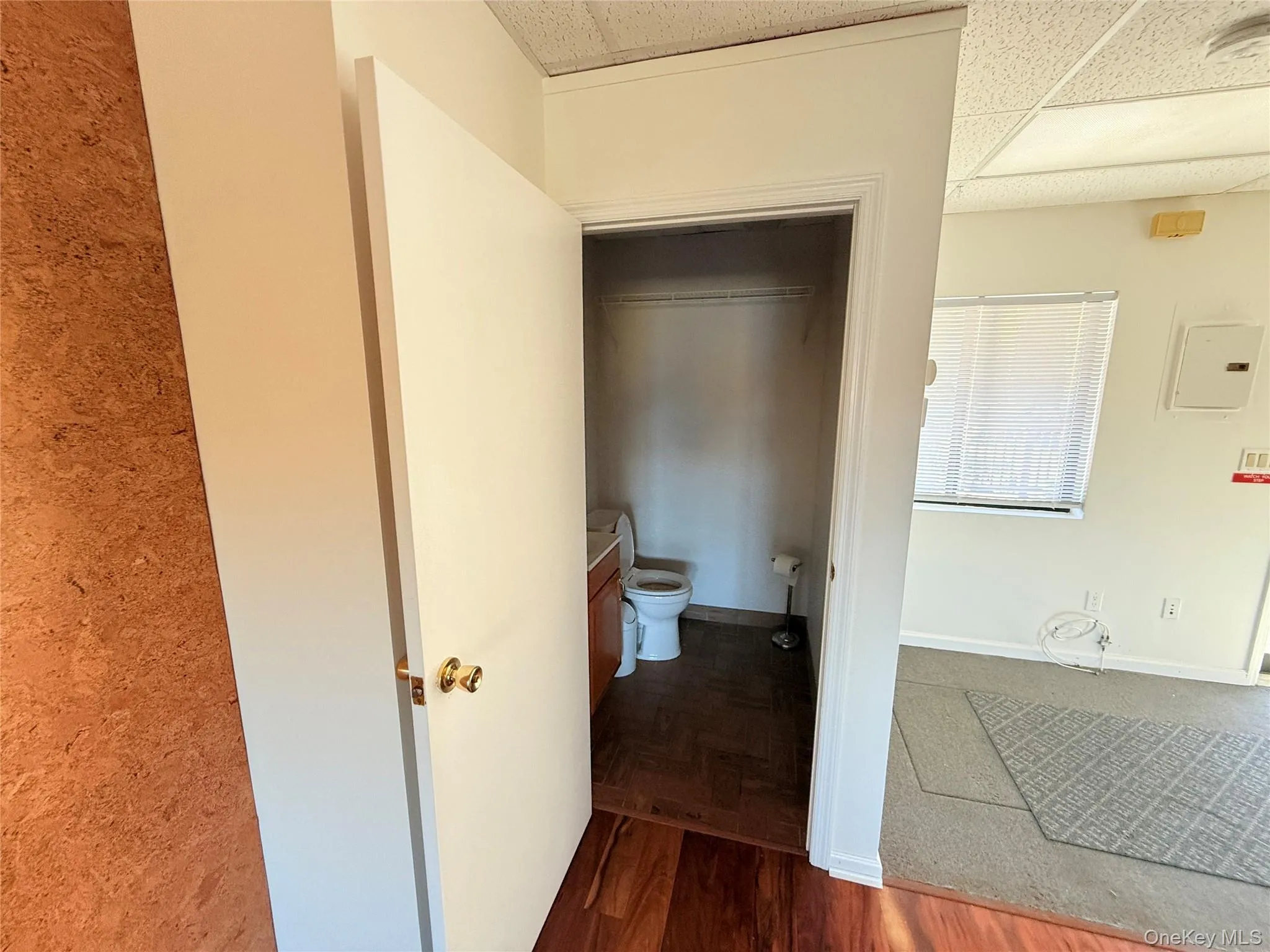 Hallway featuring baseboards, a drop ceiling, parquet floors, and electric panel Hallway featuring baseboards, a drop ceiling, parquet floors, and electric panel