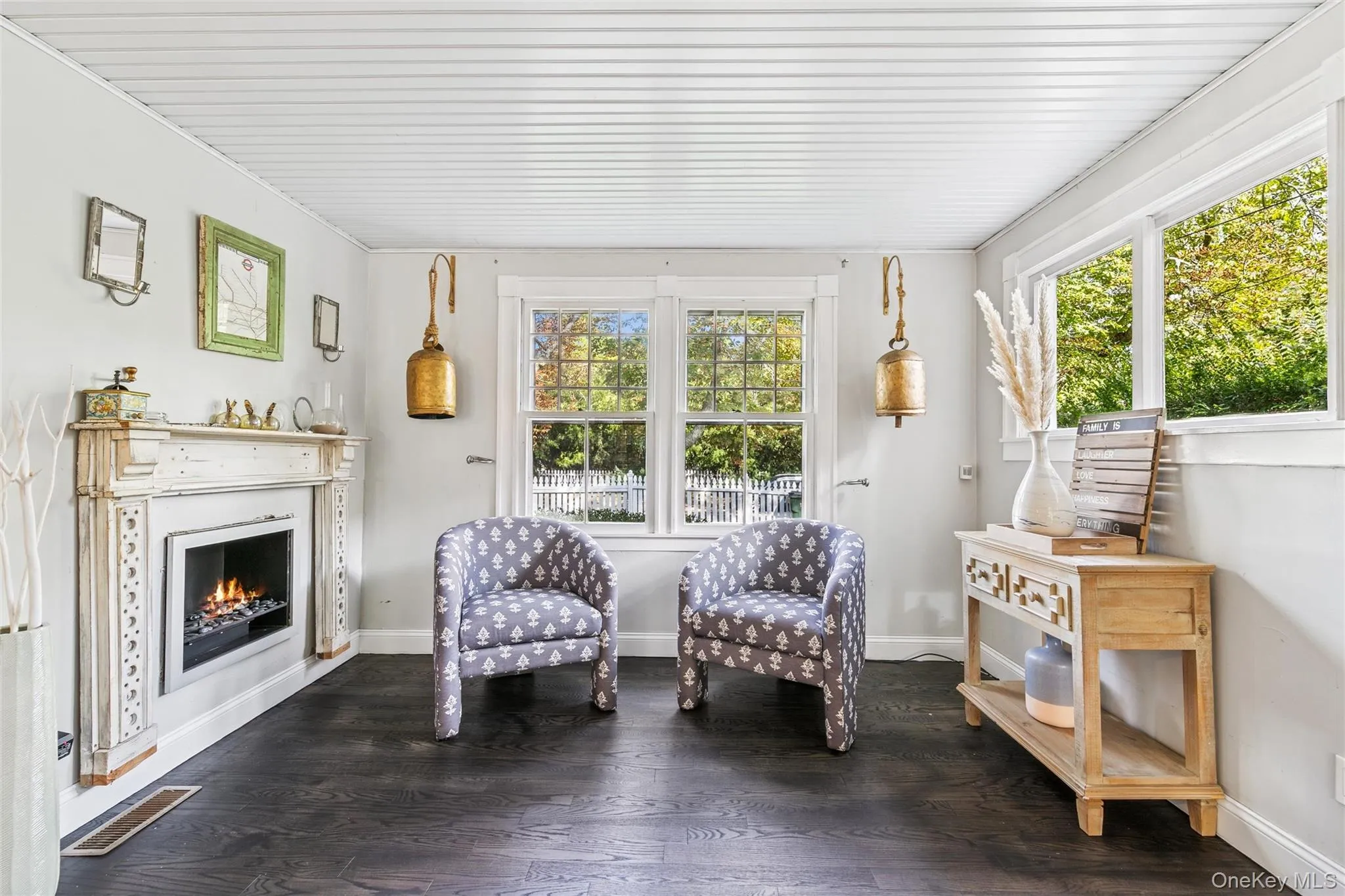 Living area with healthy amount of natural light, a lit fireplace, and dark wood-type flooring Living area with healthy amount of natural light, a lit fireplace, and dark wood-type flooring