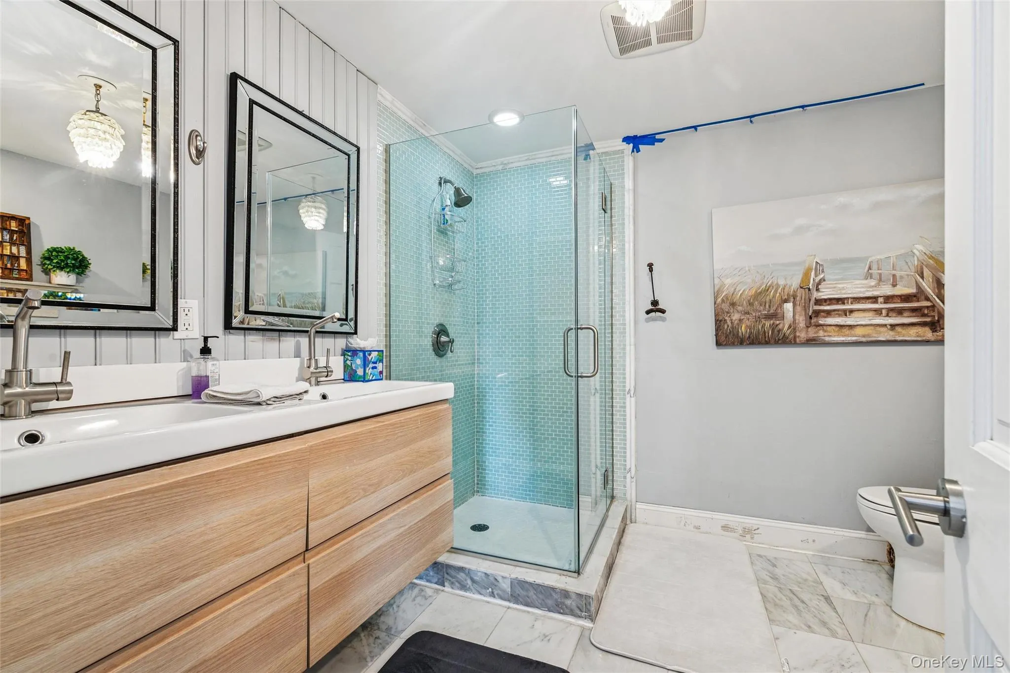 Full bathroom with double vanity, a stall shower, and light marble finish flooring Full bathroom with double vanity, a stall shower, and light marble finish flooring