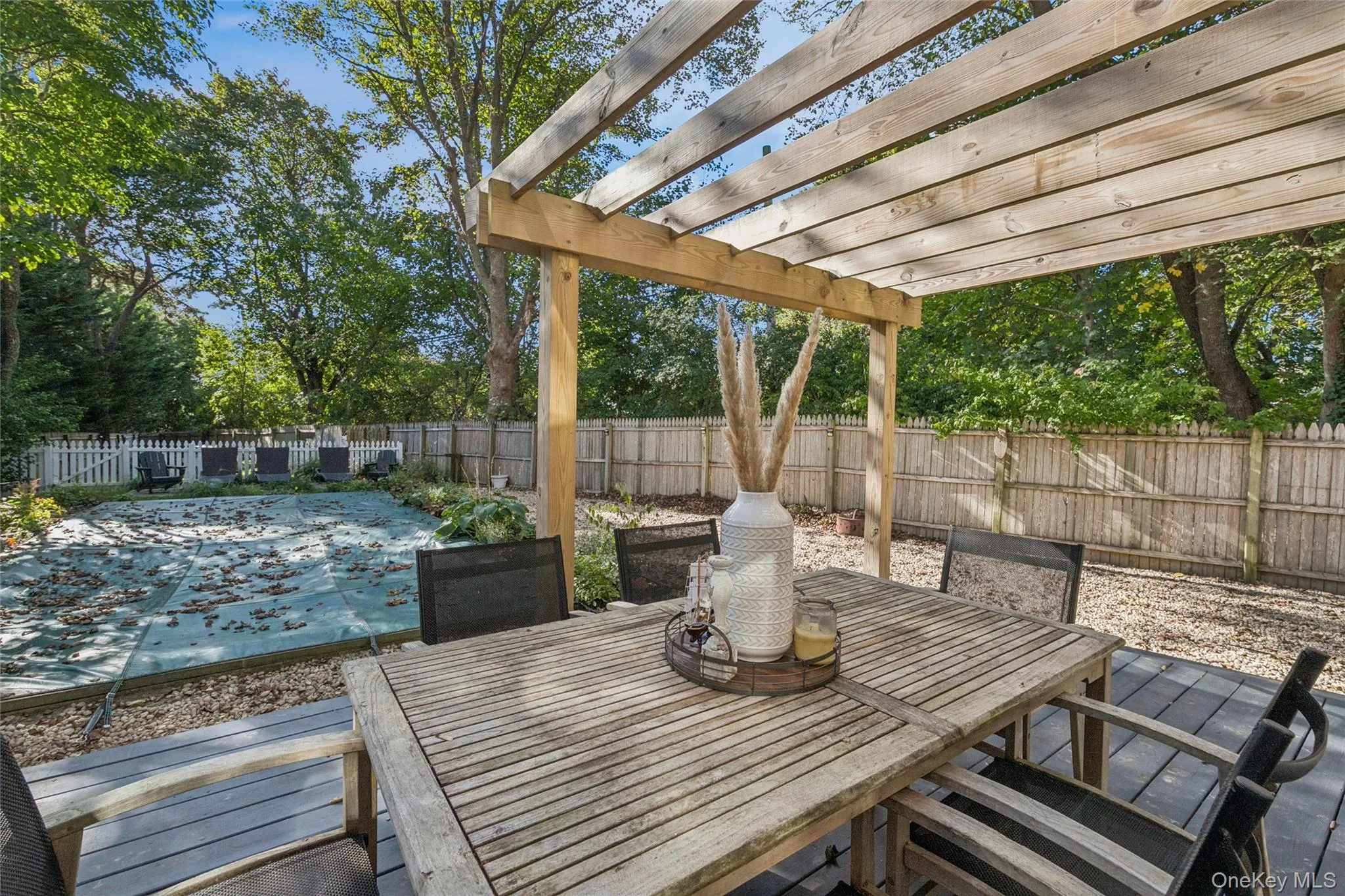 Fenced backyard with a covered pool, outdoor dining area, a pergola, and a patio Fenced backyard with a covered pool, outdoor dining area, a pergola, and a patio