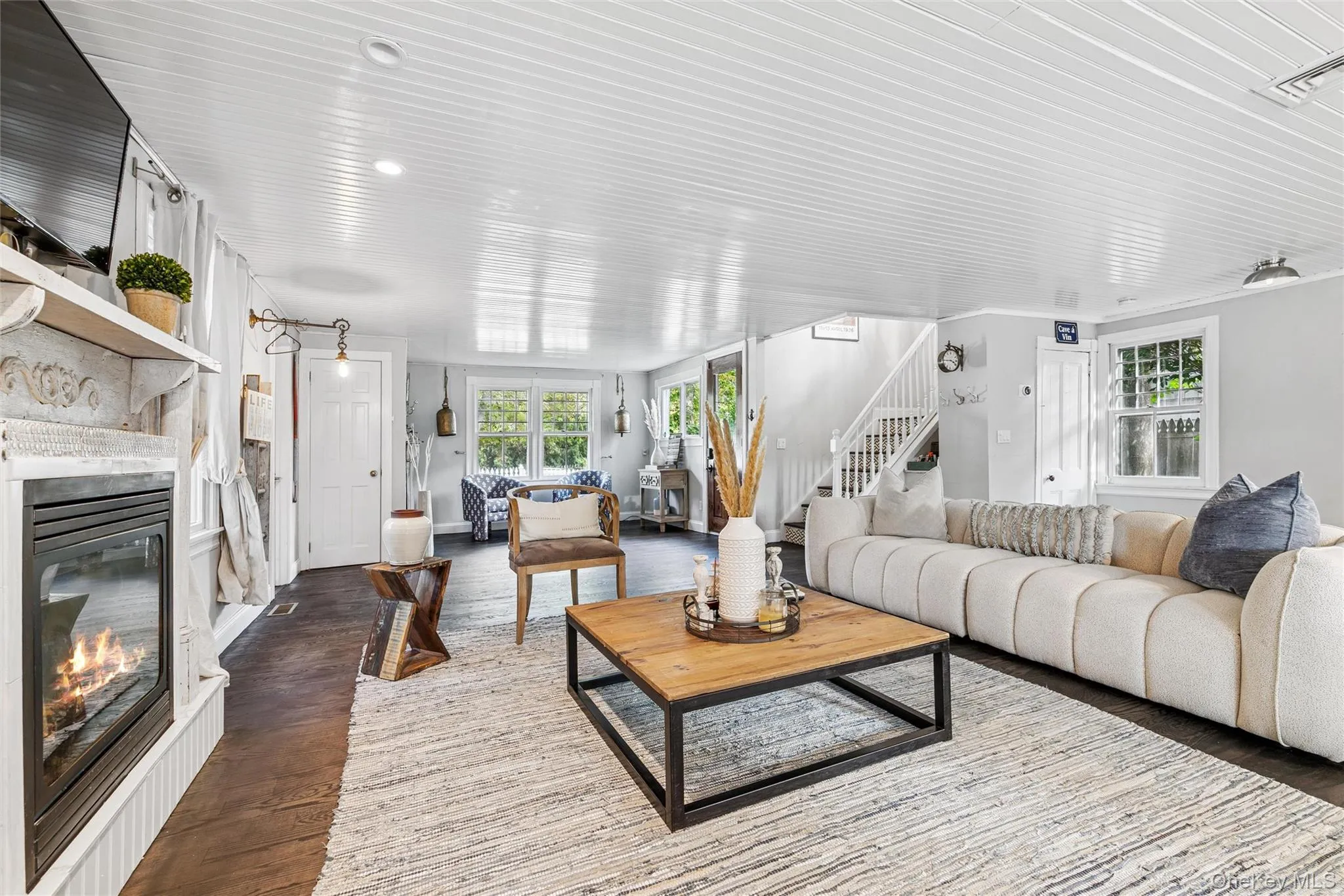 Living area with stairs, wood finished floors, and a glass covered fireplace Living area with stairs, wood finished floors, and a glass covered fireplace