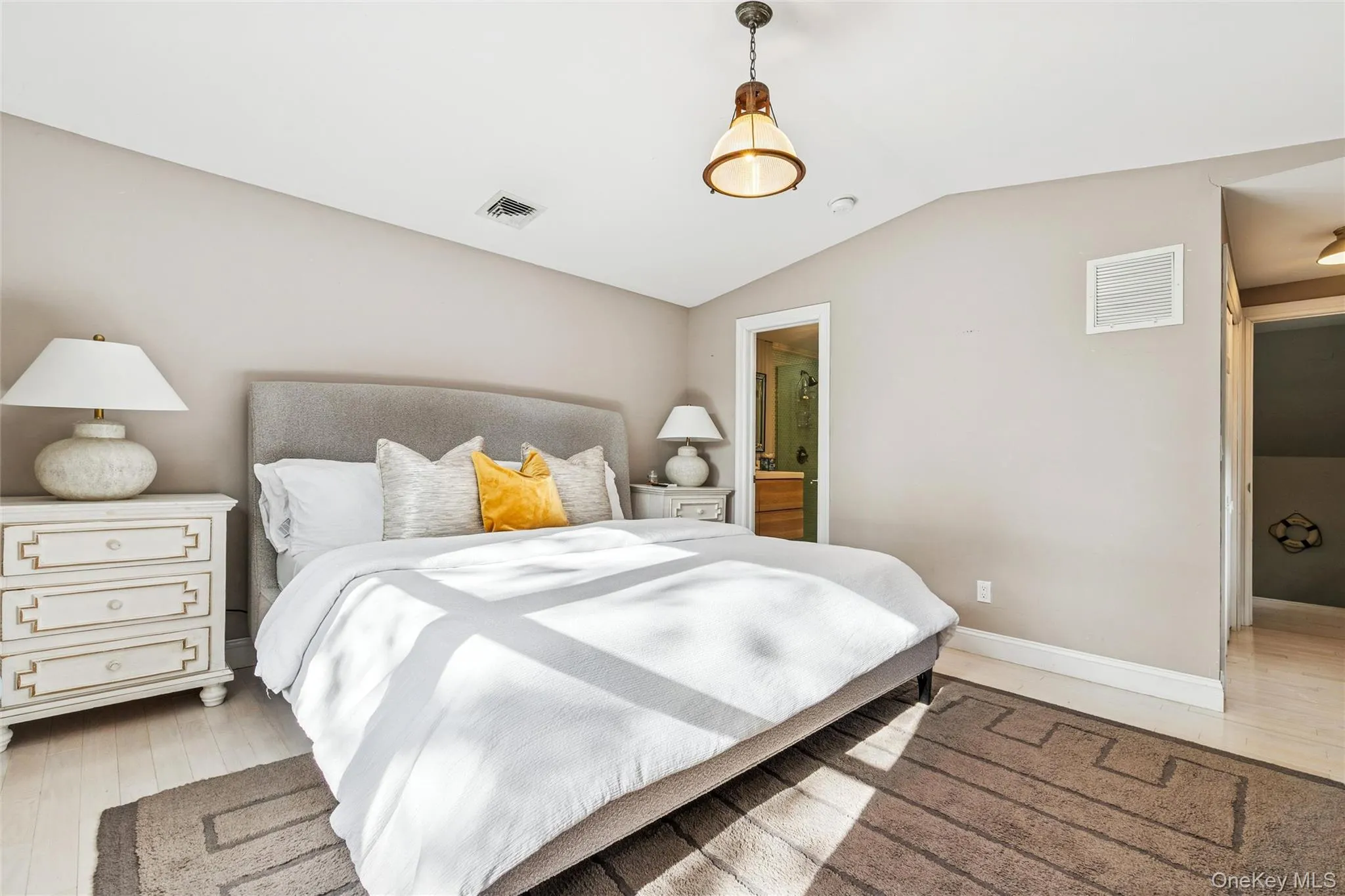 Bedroom with light wood-style flooring, vaulted ceiling, and connected bathroom Bedroom with light wood-style flooring, vaulted ceiling, and connected bathroom
