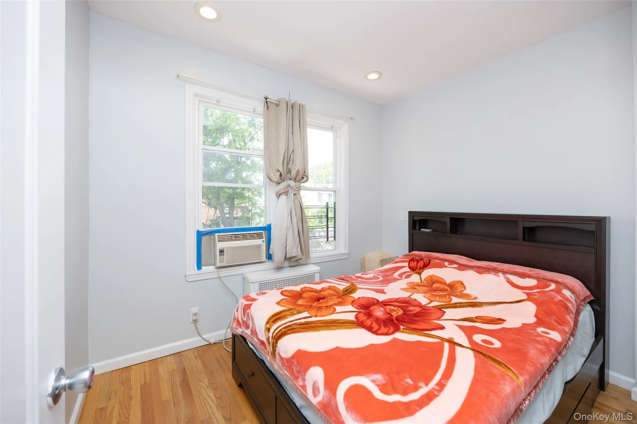 Bedroom featuring light wood-type flooring, recessed lighting, radiator heating unit, and cooling unit Bedroom featuring light wood-type flooring, recessed lighting, radiator heating unit, and cooling unit