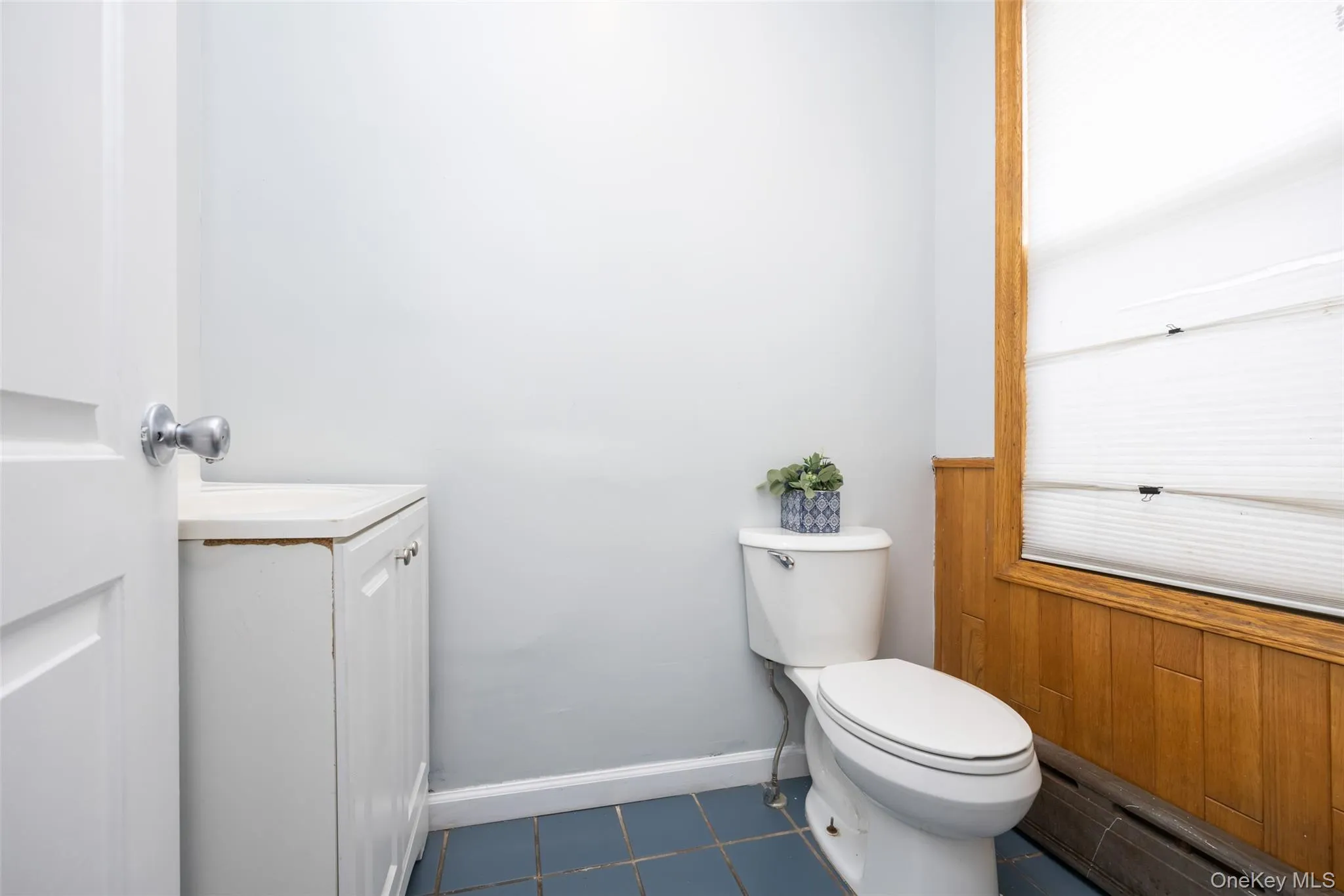 Bathroom with dark tile patterned flooring, a baseboard heating unit, and wood walls Bathroom with dark tile patterned flooring, a baseboard heating unit, and wood walls