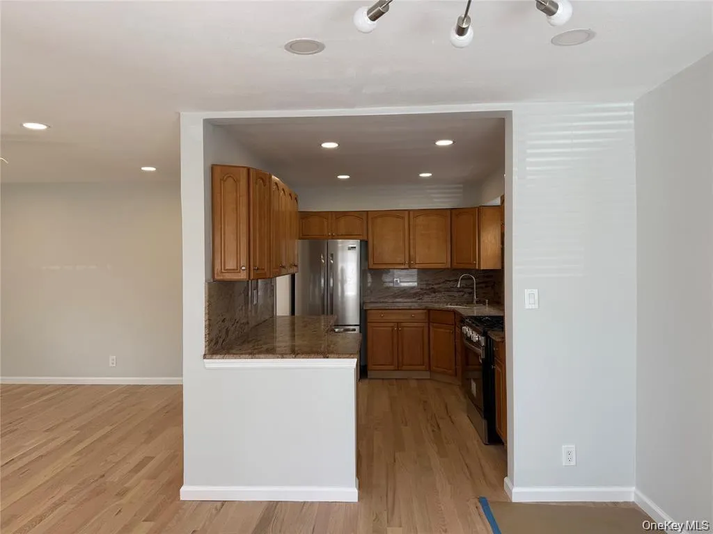 Kitchen with tasteful backsplash, dark stone countertops, light wood-type flooring, stainless steel appliances, and recessed lighting Kitchen with tasteful backsplash, dark stone countertops, light wood-type flooring, stainless steel appliances, and recessed lighting