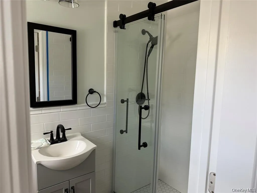 Full bathroom with vanity, a stall shower, and tile walls Full bathroom with vanity, a stall shower, and tile walls