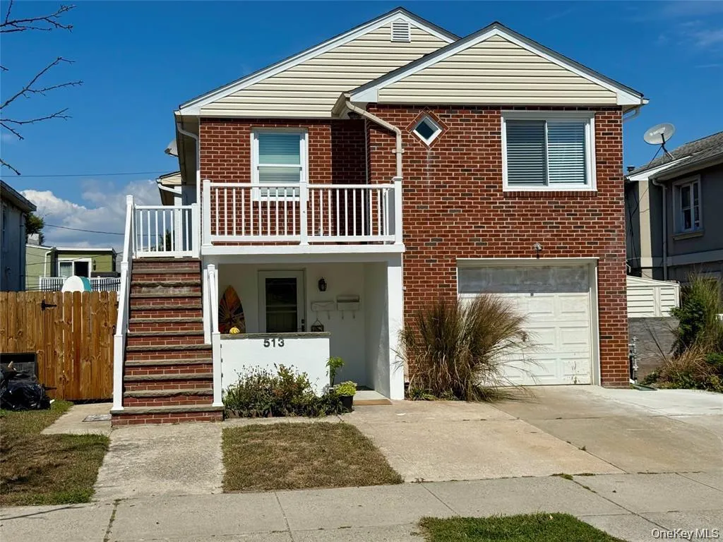 View of front facade with stairway, concrete driveway, brick siding, and a garage View of front facade with stairway, concrete driveway, brick siding, and a garage