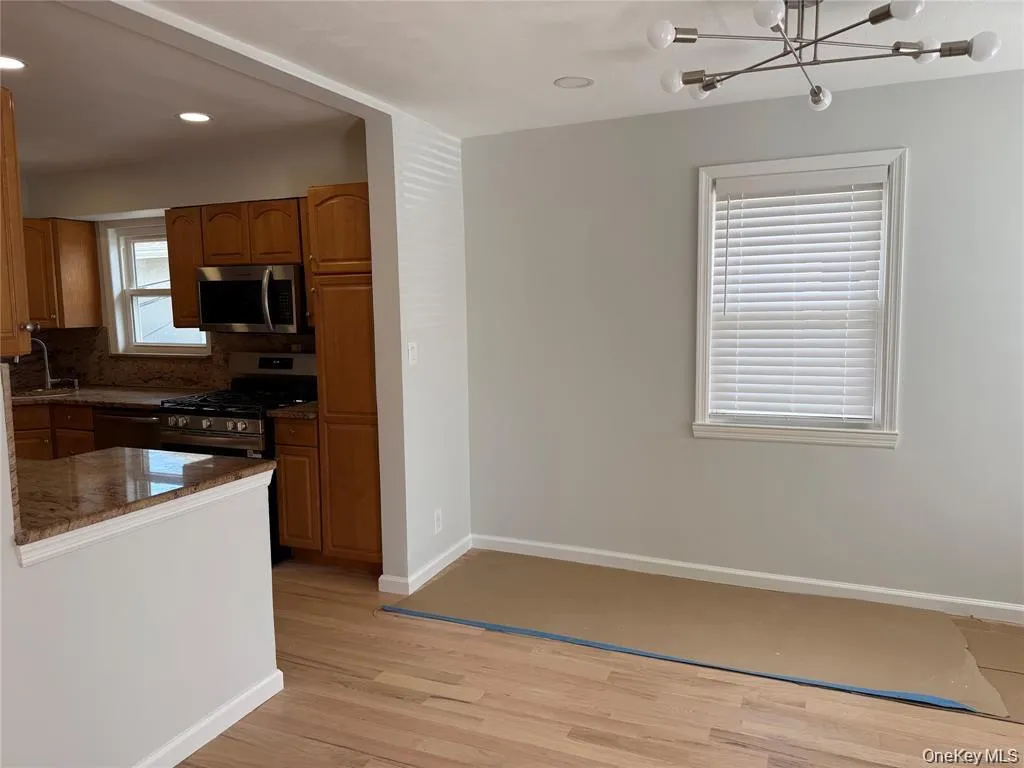 Kitchen with brown cabinets, light wood-style flooring, appliances with stainless steel finishes, dark stone countertops, and recessed lighting Kitchen with brown cabinets, light wood-style flooring, appliances with stainless steel finishes, dark stone countertops, and recessed lighting