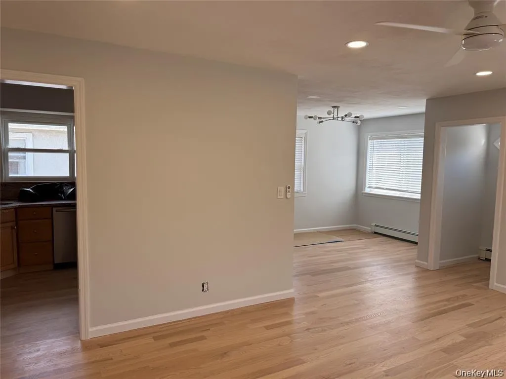 Spare room featuring recessed lighting, light wood finished floors, baseboard heating, a ceiling fan, and a chandelier Spare room featuring recessed lighting, light wood finished floors, baseboard heating, a ceiling fan, and a chandelier