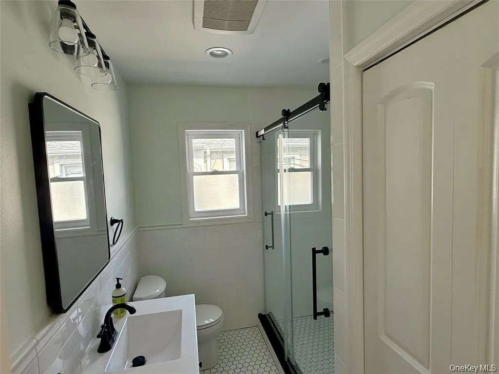 Bathroom featuring a stall shower, tile walls, wainscoting, vanity, and tile patterned floors Bathroom featuring a stall shower, tile walls, wainscoting, vanity, and tile patterned floors