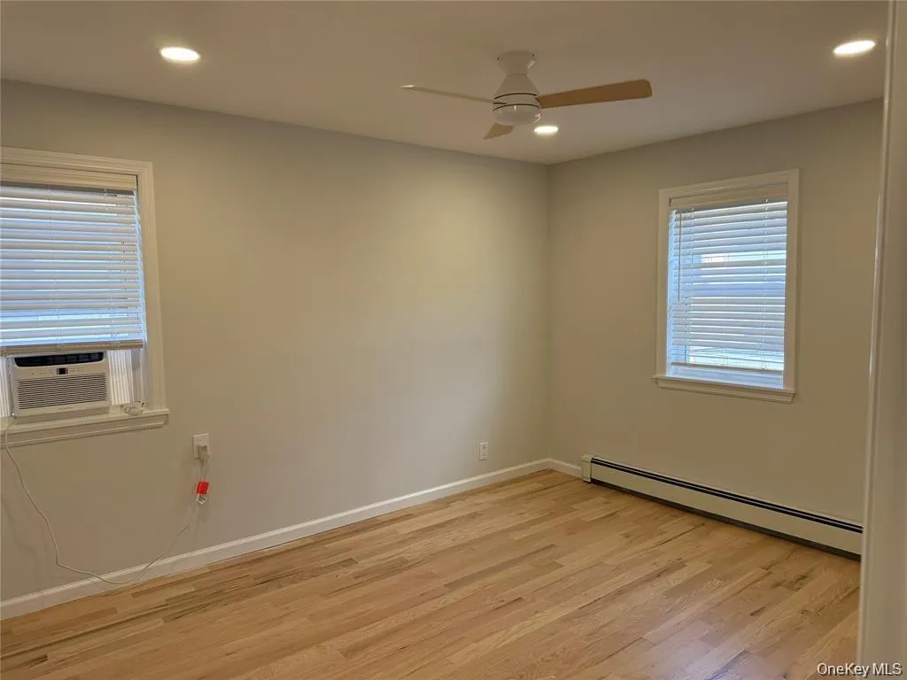 Spare room featuring a baseboard radiator, recessed lighting, light wood finished floors, cooling unit, and a ceiling fan Spare room featuring a baseboard radiator, recessed lighting, light wood finished floors, cooling unit, and a ceiling fan