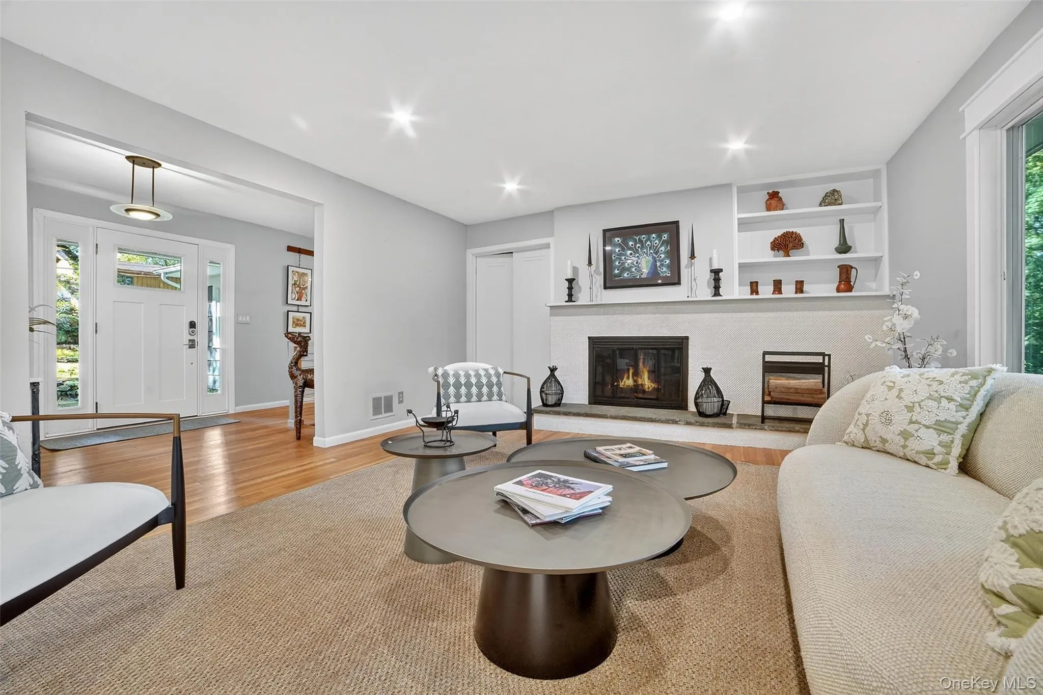 Living area with plenty of natural light, light wood-style flooring, a glass covered fireplace, and recessed lighting Living area with plenty of natural light, light wood-style flooring, a glass covered fireplace, and recessed lighting