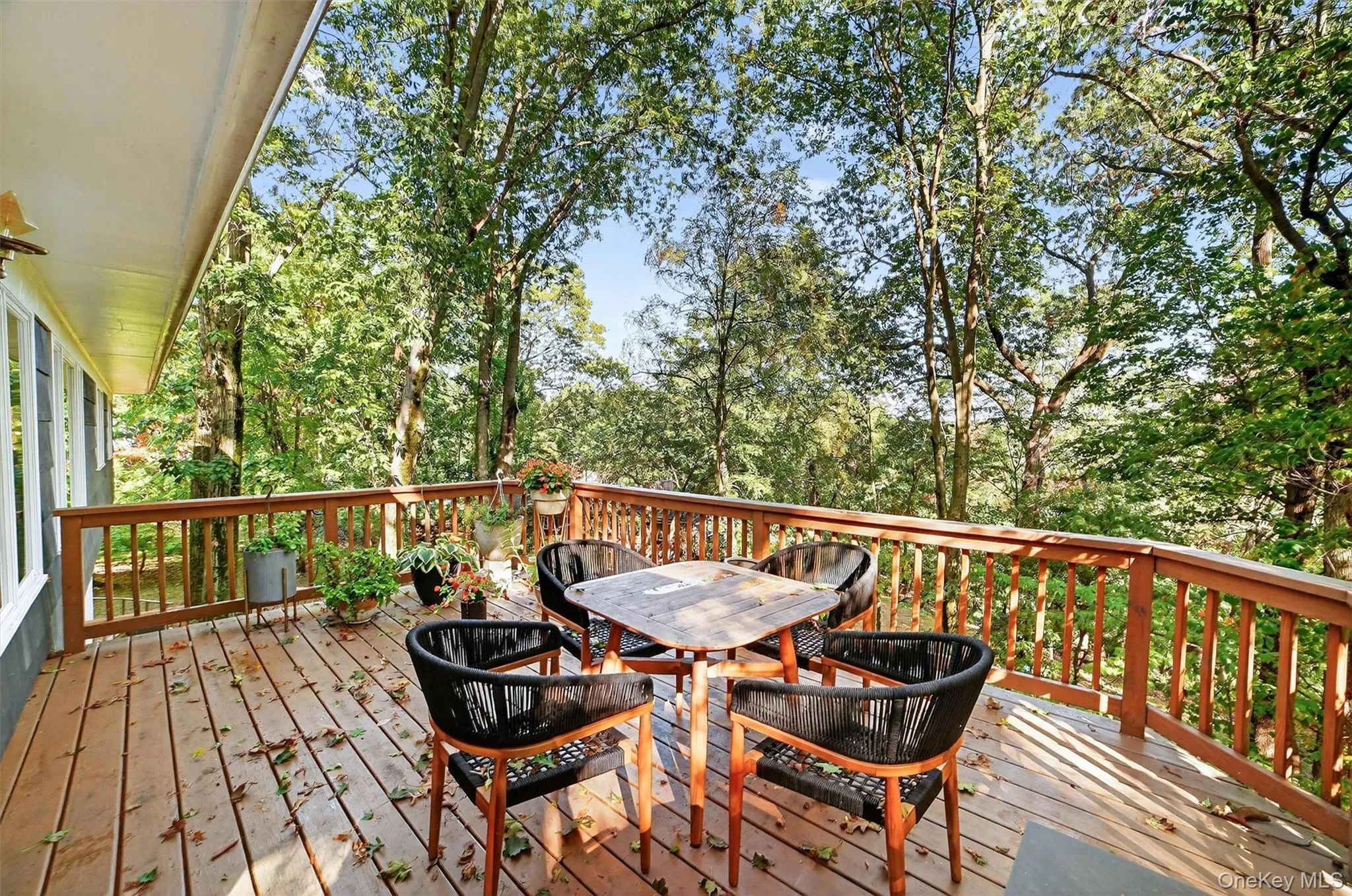 Wooden terrace featuring outdoor dining area and view of wooded area Wooden terrace featuring outdoor dining area and view of wooded area