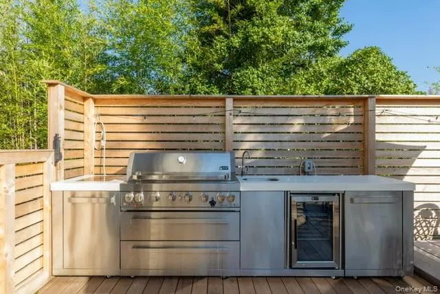 View of patio with area for grilling, wine cooler, and a wooden deck View of patio with area for grilling, wine cooler, and a wooden deck
