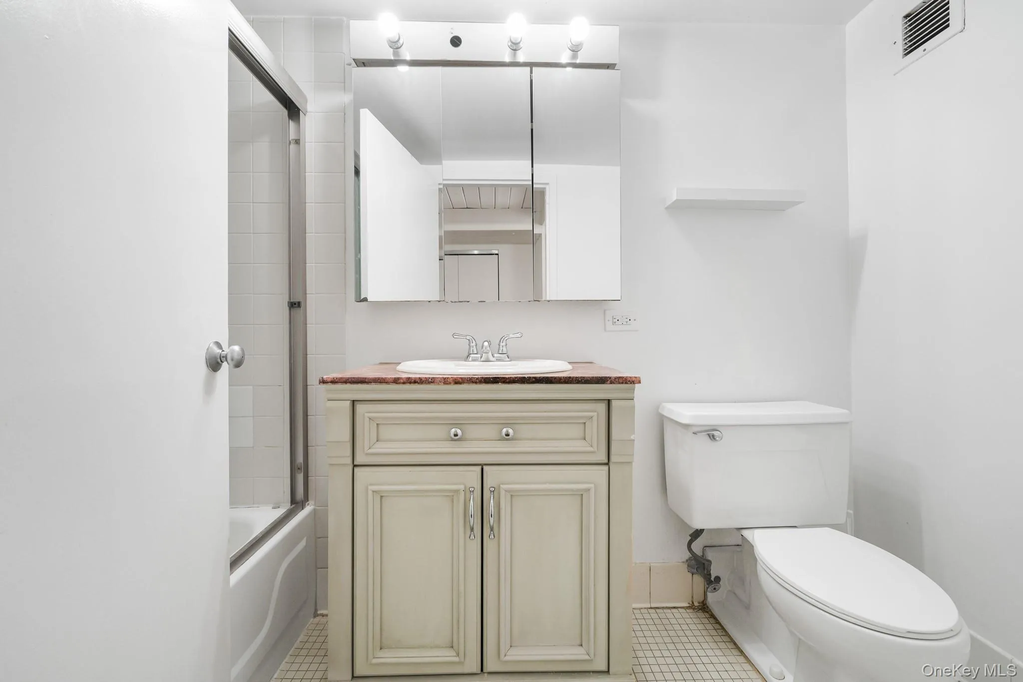 Full bathroom featuring vanity, enclosed tub / shower combo, and light tile patterned flooring Full bathroom featuring vanity, enclosed tub / shower combo, and light tile patterned flooring