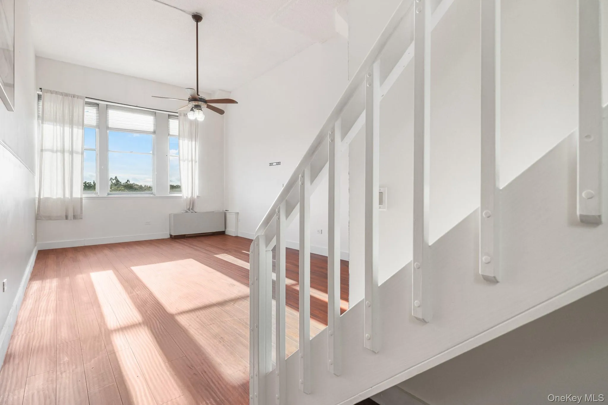 Staircase with a ceiling fan and on looking living room with wood finished floors Staircase with a ceiling fan and on looking living room with wood finished floors