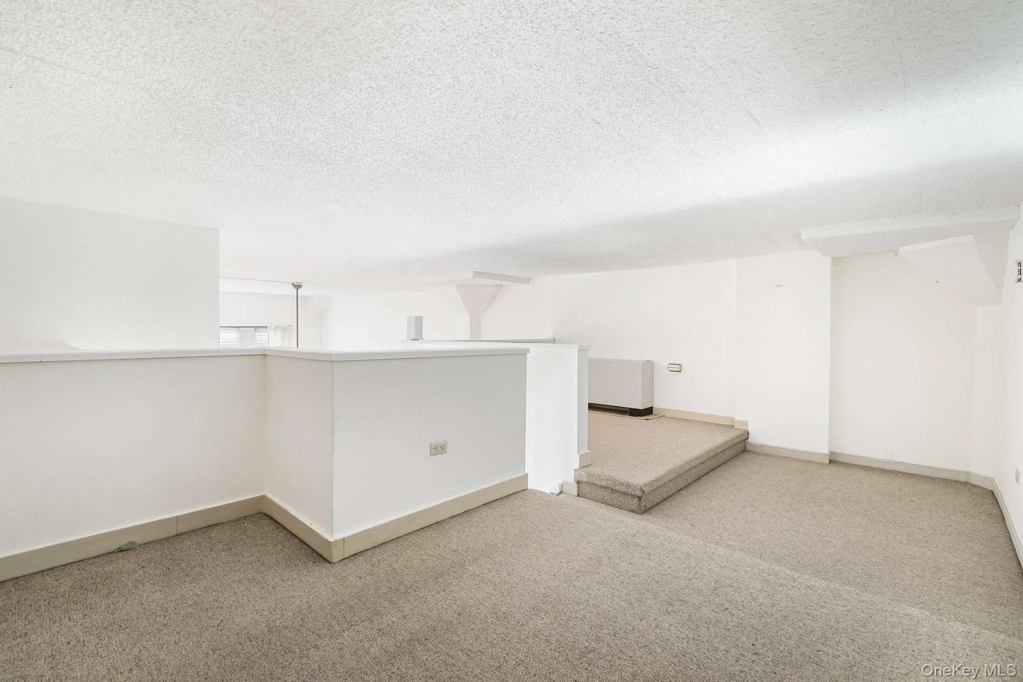 Carpeted spare room featuring a textured ceiling and baseboards Carpeted spare room featuring a textured ceiling and baseboards