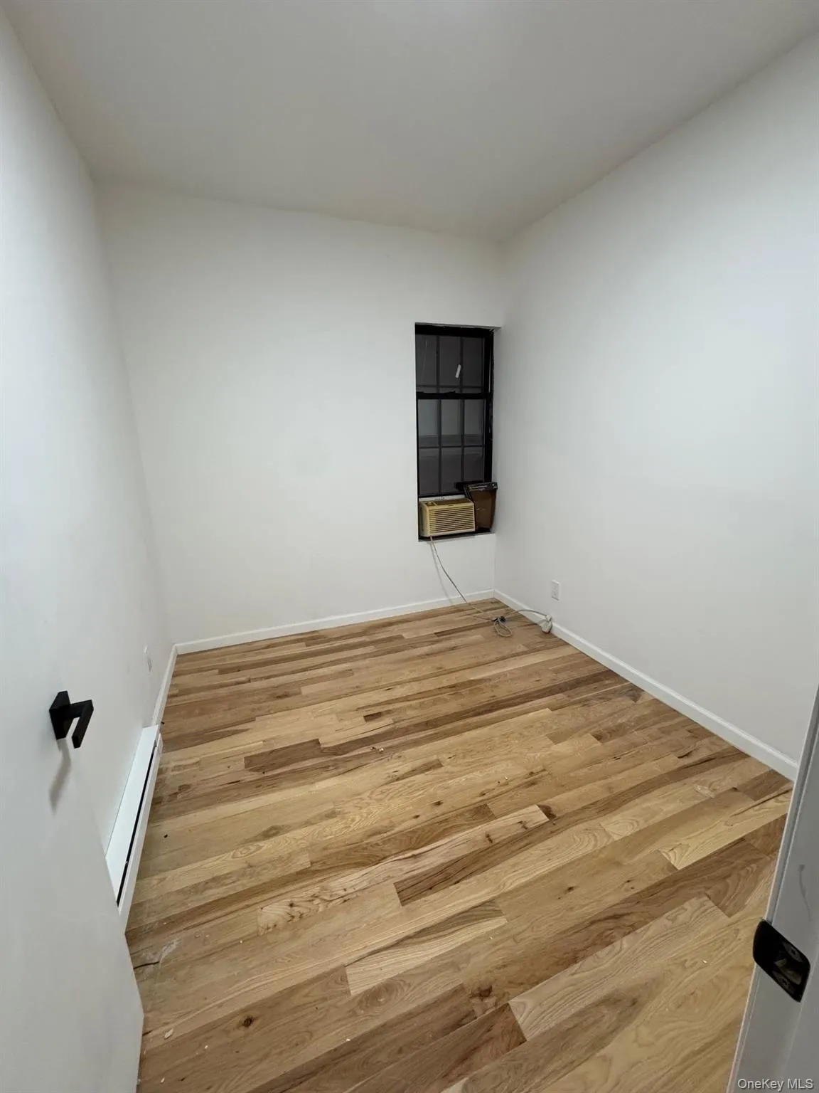 Empty room featuring light wood finished floors and a baseboard heating unit Empty room featuring light wood finished floors and a baseboard heating unit