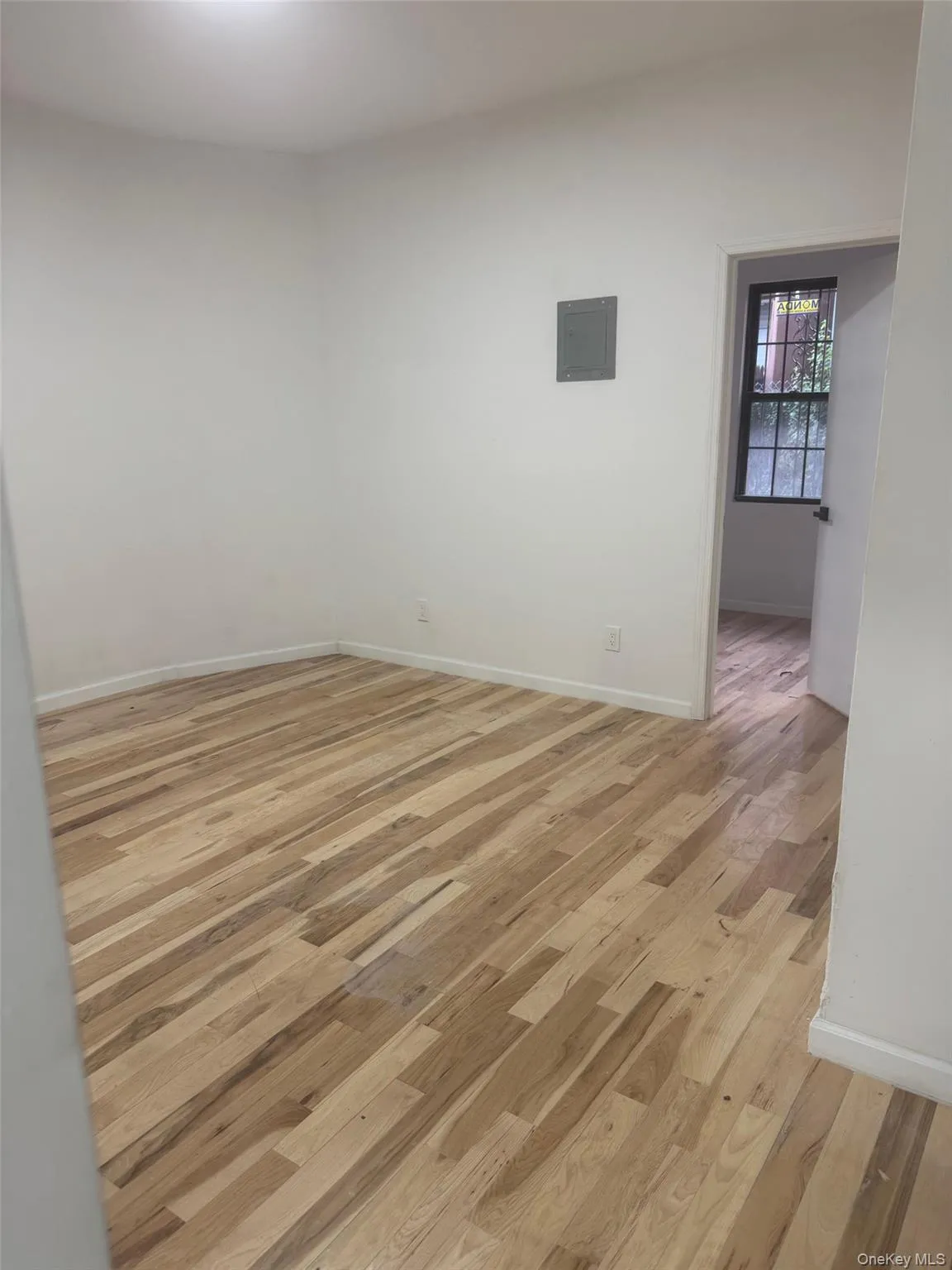 Empty room featuring light wood-style floors and electric panel Empty room featuring light wood-style floors and electric panel