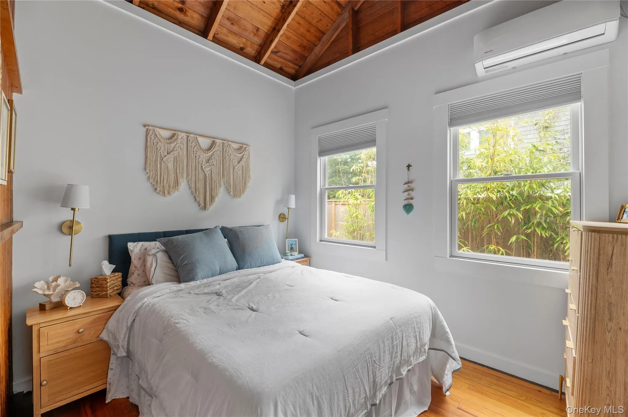 Bedroom featuring wooden ceiling, an AC wall unit, and wood finished floors Bedroom featuring wooden ceiling, an AC wall unit, and wood finished floors