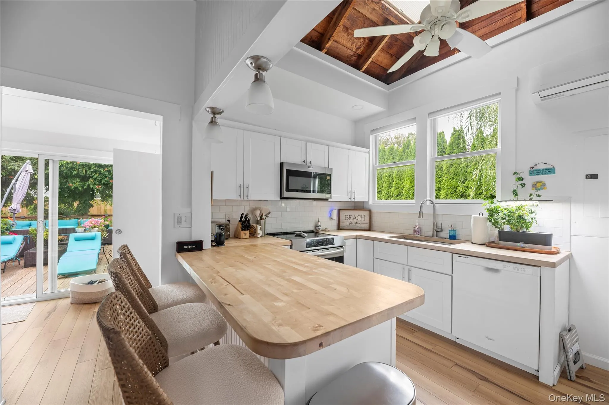 Kitchen with a breakfast bar area, white cabinets, a peninsula, backsplash, and stainless steel appliances Kitchen with a breakfast bar area, white cabinets, a peninsula, backsplash, and stainless steel appliances
